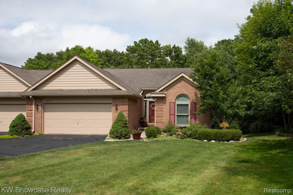 1128 Eagle Nest Dr, Milford, MI 48381 - single story home featuring a garage, brick siding, asphalt driveway, a front lawn, and a shingled roof