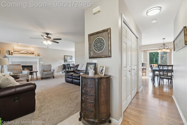 9145 Woodridge Dr, Davison, MI 48423 - living room featuring a tile fireplace, a ceiling fan, a chandelier, and light wood-type flooring