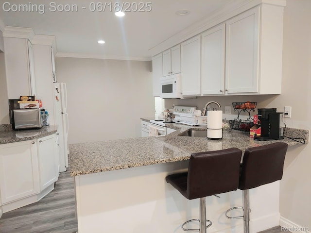 679 Judith St, Westland, MI 48186 - kitchen with white appliances, light stone counters, white cabinets, a breakfast bar area, and light wood-style floors