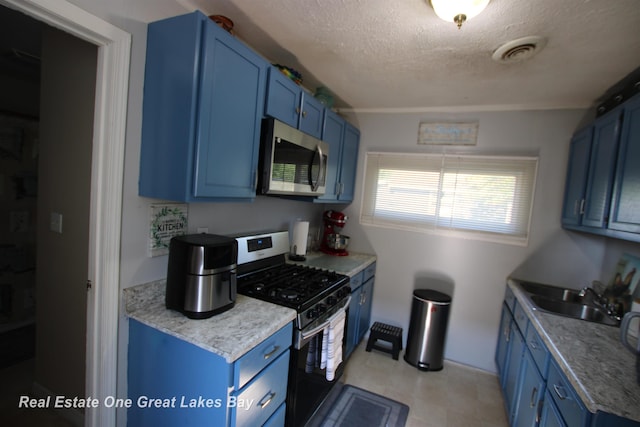 1521 Stanley St, Saginaw, MI 48602 - kitchen with blue cabinets, stainless steel appliances, a textured ceiling, light floors, and light countertops