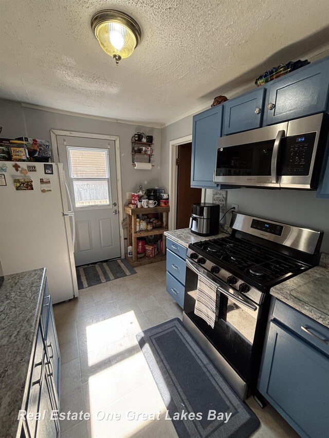 1521 Stanley St, Saginaw, MI 48602 - kitchen featuring stainless steel appliances, blue cabinetry, a textured ceiling, and light countertops