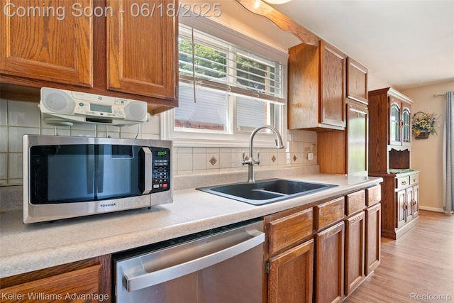 37862 Parkhurst St, Livonia, MI 48154 - kitchen featuring appliances with stainless steel finishes, brown cabinets, light wood-style flooring, and decorative backsplash