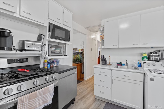 11228 Hudson Ave, Warren, MI 48089 - kitchen featuring stainless steel gas range oven, washer / dryer, black microwave, light wood-style floors, and white cabinets