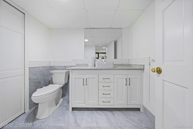 52615 Seven Oaks Dr, Shelby Twp, MI 48316 - bathroom featuring a drop ceiling, vanity, marble finish flooring, and a wainscoted wall