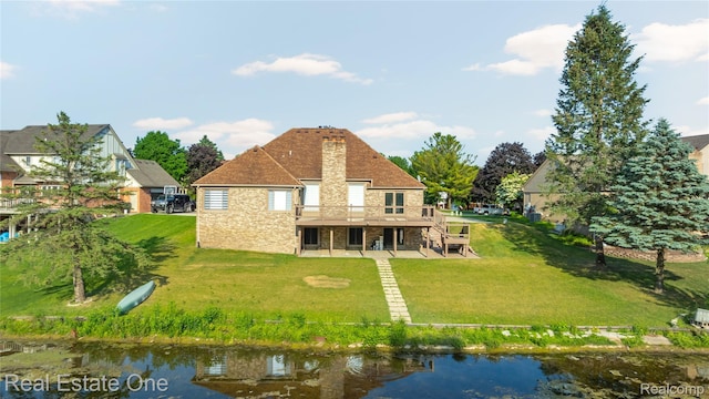 52615 Seven Oaks Dr, Shelby Twp, MI 48316 - rear view of property featuring stone siding, a deck with water view, a lawn, and a patio area