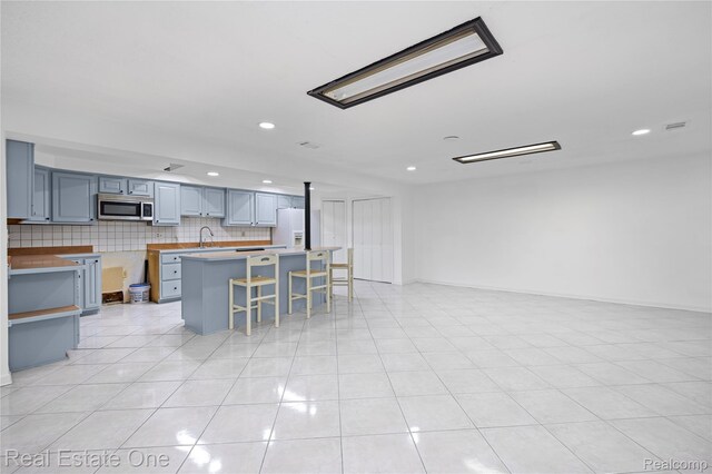 52615 Seven Oaks Dr, Shelby Twp, MI 48316 - kitchen featuring stainless steel microwave, white refrigerator with ice dispenser, a kitchen bar, recessed lighting, and a center island
