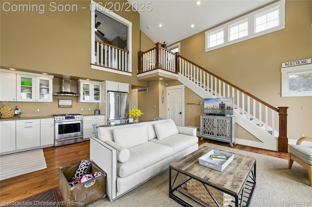 11693 Kenton Dr, Whitmore Lake, MI 48189 - living area featuring stairway, a towering ceiling, wood finished floors, plenty of natural light, and recessed lighting