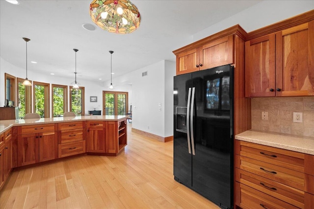 4679 Forest Ridge Dr, Holland, MI 49423 - kitchen featuring black refrigerator with ice dispenser, brown cabinetry, backsplash, light wood-style floors, and hanging light fixtures