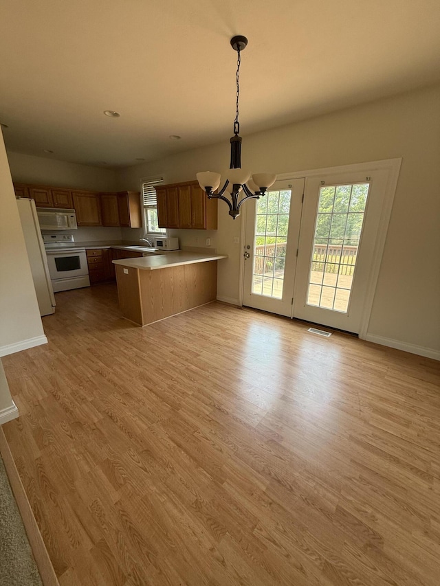5798 Wacker Dr, Stevensville, MI 49127 - kitchen with white appliances, a chandelier, open floor plan, a peninsula, and light wood finished floors