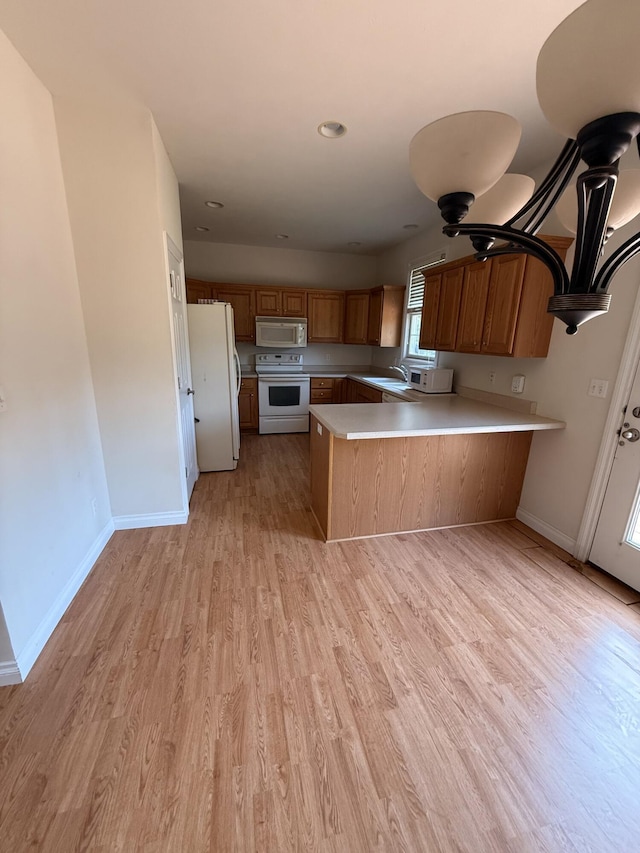 5798 Wacker Dr, Stevensville, MI 49127 - kitchen with white appliances, a peninsula, brown cabinets, light countertops, and recessed lighting