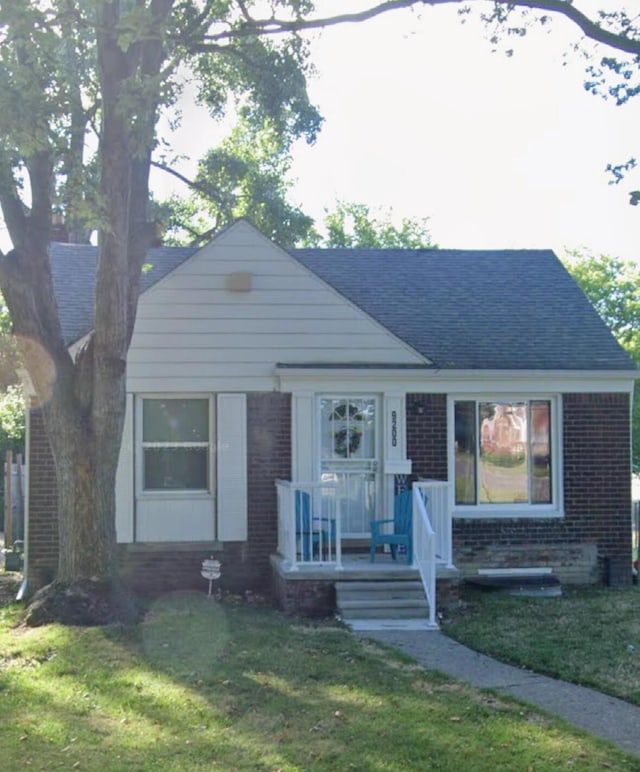 9200 Camley St, Detroit, MI 48224 - view of front of house with brick siding, a front yard, and a shingled roof