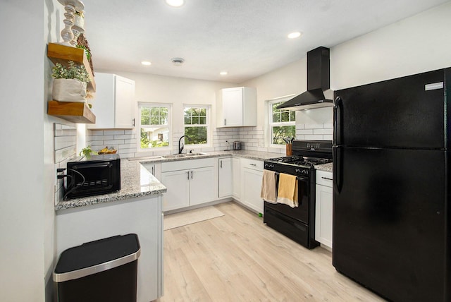 701 E Alice St, Whitehall, MI 49461 - kitchen with black appliances, wall chimney range hood, light stone counters, white cabinetry, and tasteful backsplash