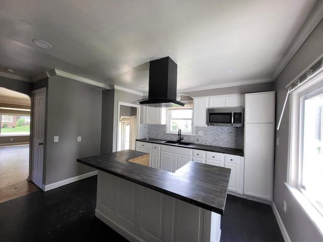 23077 Piper Ave, Eastpointe, MI 48021 - kitchen with stainless steel microwave, island exhaust hood, backsplash, white cabinetry, and crown molding