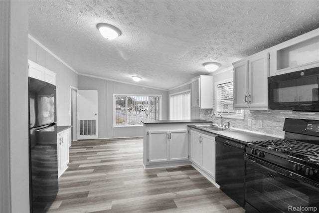 39500 W Warren Rd, Canton, MI 48187 - kitchen with black appliances, a peninsula, lofted ceiling, light wood-style flooring, and white cabinetry