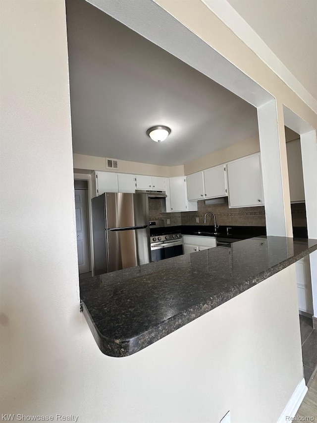 490 N Fox Hills Dr N Unit 2, Bloomfield Hills, MI 48304 - kitchen featuring stainless steel appliances, white cabinets, a peninsula, dark stone counters, and tasteful backsplash