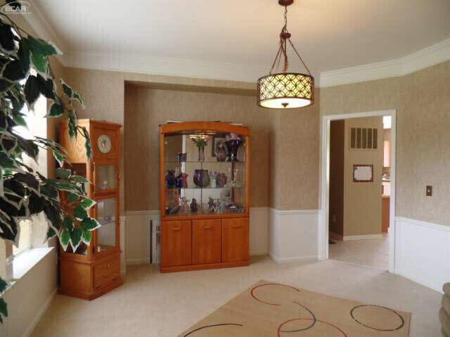 6296 Moonstone Dr, Grand Blanc, MI 48439 - dining space featuring a wainscoted wall, light carpet, and ornamental molding