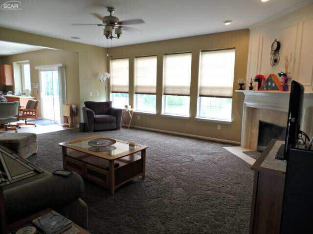 6296 Moonstone Dr, Grand Blanc, MI 48439 - carpeted living room with plenty of natural light, a ceiling fan, and a fireplace with flush hearth