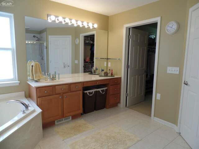 6296 Moonstone Dr, Grand Blanc, MI 48439 - full bathroom featuring a stall shower, tile patterned flooring, a garden tub, vanity, and a walk in closet