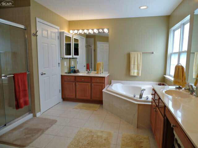 6296 Moonstone Dr, Grand Blanc, MI 48439 - bathroom featuring two vanities, a garden tub, a shower stall, tile patterned flooring, and recessed lighting
