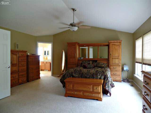 6296 Moonstone Dr, Grand Blanc, MI 48439 - bedroom with lofted ceiling, light colored carpet, connected bathroom, and a ceiling fan