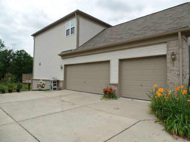 6296 Moonstone Dr, Grand Blanc, MI 48439 - view of side of property with an attached garage, driveway, and brick siding