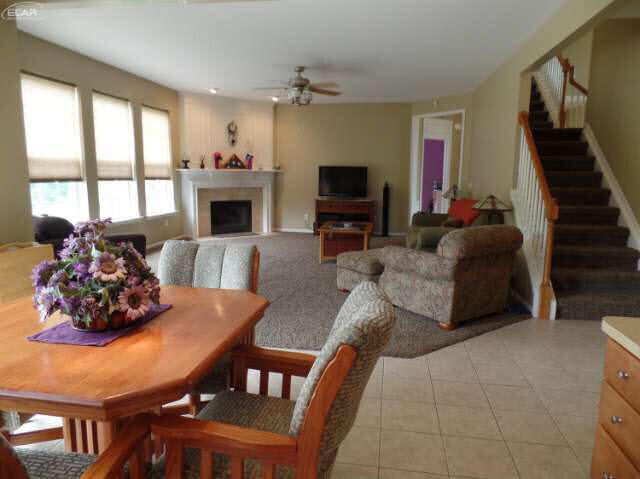6296 Moonstone Dr, Grand Blanc, MI 48439 - dining area featuring ceiling fan, stairway, a fireplace, and light tile patterned floors