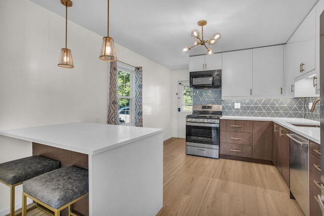 1603 Park Rd, Jackson, MI 49203 - kitchen featuring stainless steel appliances, light wood-style flooring, a kitchen bar, white cabinets, and tasteful backsplash