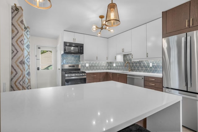 1603 Park Rd, Jackson, MI 49203 - kitchen with appliances with stainless steel finishes, light countertops, decorative backsplash, and a chandelier