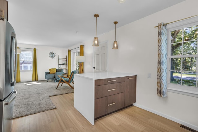 1603 Park Rd, Jackson, MI 49203 - kitchen featuring light wood-style floors, freestanding refrigerator, light countertops, open floor plan, and hanging light fixtures