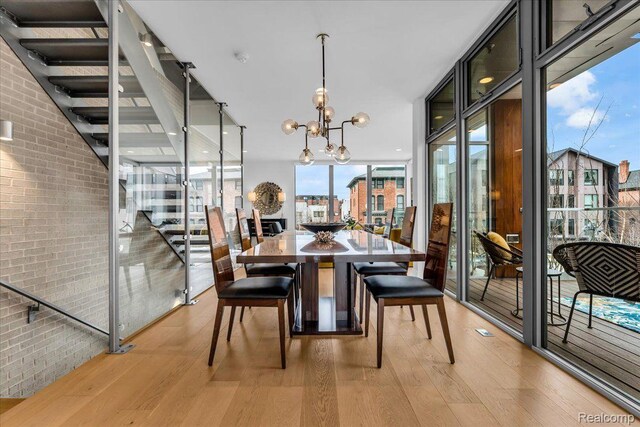 248 Alfred St, Detroit, MI 48201 - dining space with light wood-style flooring, a wall of windows, brick wall, and a chandelier