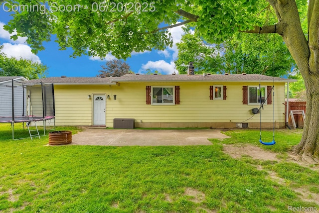 312 Airport Dr, Holly, MI 48442 - back of house with a trampoline, a patio, a lawn, and a chimney