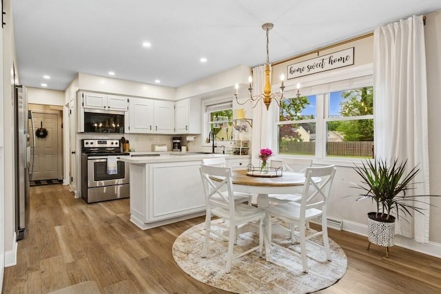 3108 Kim St, Saint Joseph, MI 49085 - kitchen with stainless steel appliances, a chandelier, wood finished floors, light countertops, and tasteful backsplash