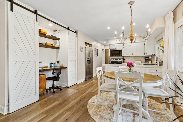 3108 Kim St, Saint Joseph, MI 49085 - dining room featuring a barn door, a chandelier, an office area, light wood-style flooring, and recessed lighting