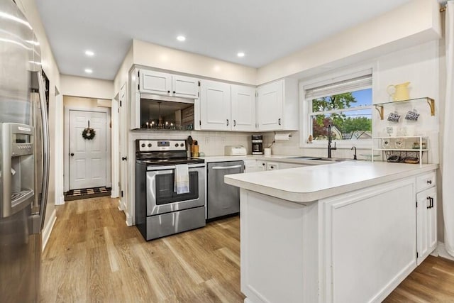 3108 Kim St, Saint Joseph, MI 49085 - kitchen with appliances with stainless steel finishes, a peninsula, light countertops, decorative backsplash, and white cabinetry