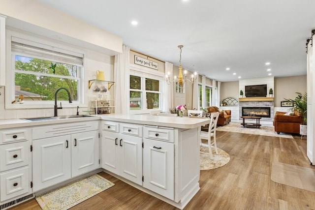 3108 Kim St, Saint Joseph, MI 49085 - kitchen featuring a peninsula, a chandelier, white cabinets, light countertops, and wood finished floors