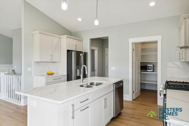 1827 Stratford Ln NW, Grand Rapids, MI 49534 - kitchen featuring stainless steel appliances, vaulted ceiling, light wood finished floors, decorative light fixtures, and light stone counters
