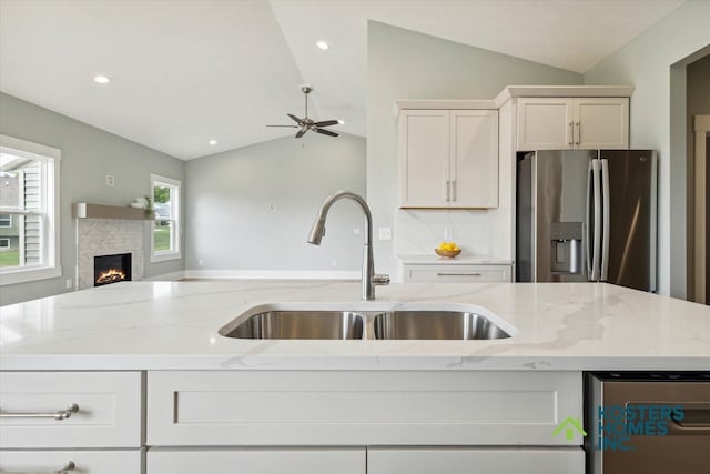 1827 Stratford Ln NW, Grand Rapids, MI 49534 - kitchen with stainless steel appliances, open floor plan, vaulted ceiling, a lit fireplace, and light stone countertops