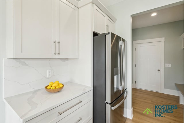 1827 Stratford Ln NW, Grand Rapids, MI 49534 - kitchen with stainless steel fridge with ice dispenser, light stone countertops, light wood-style flooring, recessed lighting, and white cabinetry