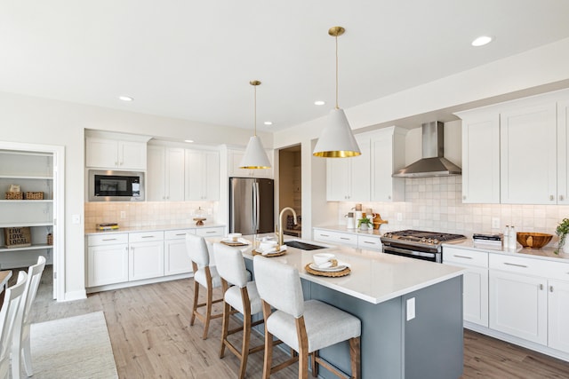 8167 Turning Stone, Kalamazoo, MI 49009 - kitchen featuring wall chimney exhaust hood, appliances with stainless steel finishes, decorative backsplash, a kitchen breakfast bar, and an island with sink