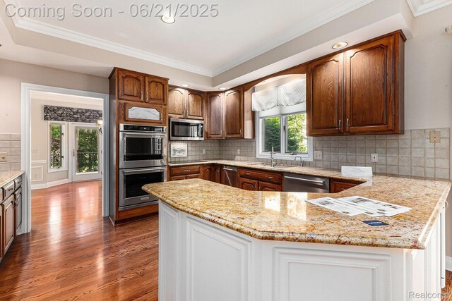 5387 Bristol Parke Dr, Clarkston, MI 48348 - kitchen featuring appliances with stainless steel finishes, wood finished floors, a peninsula, tasteful backsplash, and crown molding