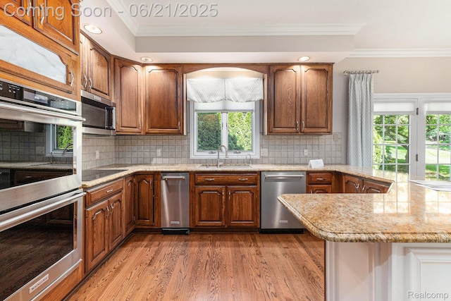 5387 Bristol Parke Dr, Clarkston, MI 48348 - kitchen with appliances with stainless steel finishes, ornamental molding, light wood-type flooring, a peninsula, and light stone counters