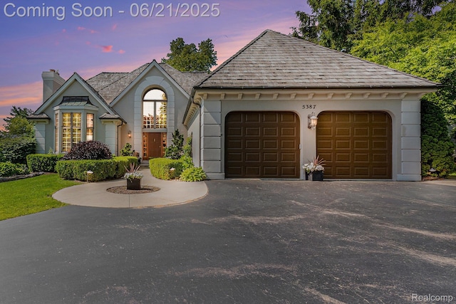 5387 Bristol Parke Dr, Clarkston, MI 48348 - french country style house with asphalt driveway, a chimney, and an attached garage