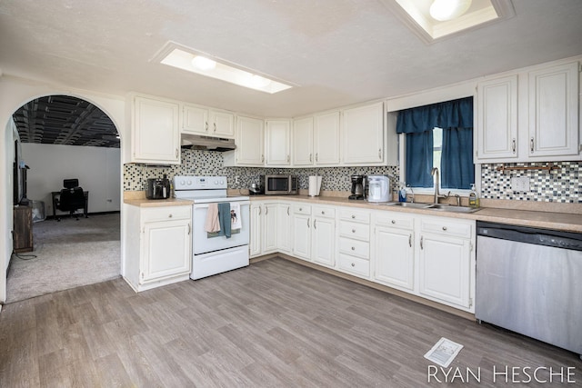 10340 Kartz Rd, Greenville, MI 48838 - kitchen with stainless steel appliances, under cabinet range hood, white cabinetry, light countertops, and backsplash