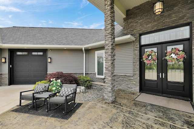 7074 S Ainger Rd, Olivet, MI 49076 - property entrance with stone siding, french doors, roof with shingles, driveway, and an attached garage