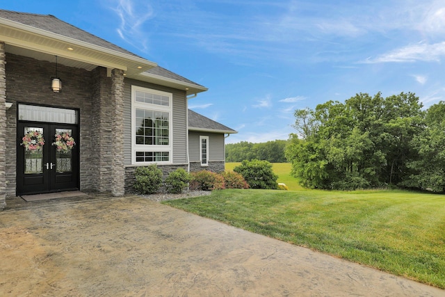 7074 S Ainger Rd, Olivet, MI 49076 - view of exterior entry featuring stone siding, french doors, a yard, and a shingled roof