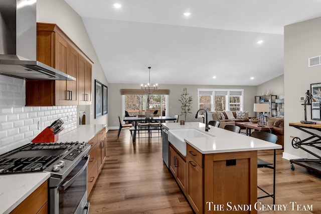 17947 Spring Tree Ct, Spring Lake, MI 49456 - kitchen featuring wall chimney range hood, appliances with stainless steel finishes, a kitchen breakfast bar, wood finished floors, and brown cabinetry