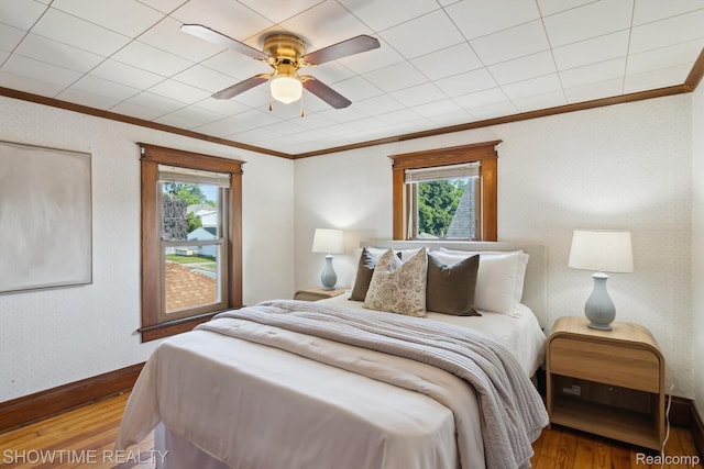 34 Charles St, Hillsdale, MI 49242 - bedroom with crown molding, wood finished floors, multiple windows, wallpapered walls, and ceiling fan