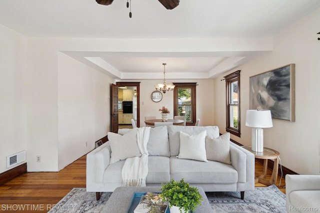 34 Charles St, Hillsdale, MI 49242 - living area with a chandelier, wood finished floors, ceiling fan, and a tray ceiling
