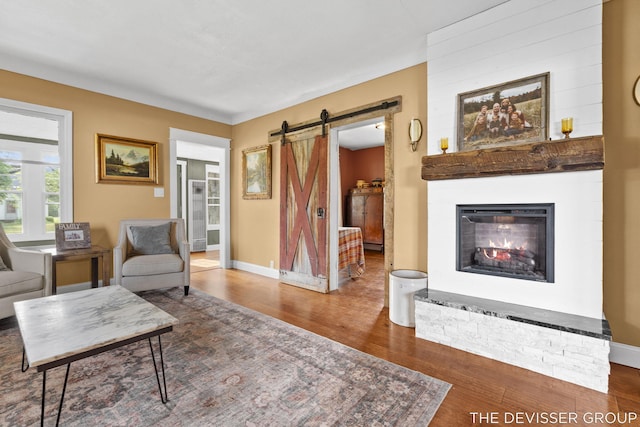 3665 47th St, Hamilton, MI 49419 - living room with a barn door, wood finished floors, and a warm lit fireplace