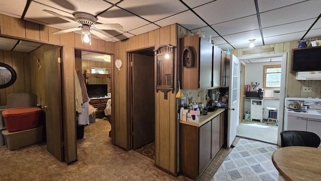 211 Skocelas Rd N, Manistee, MI 49660 - kitchen featuring carpet floors, wooden walls, range hood, light countertops, and ceiling fan